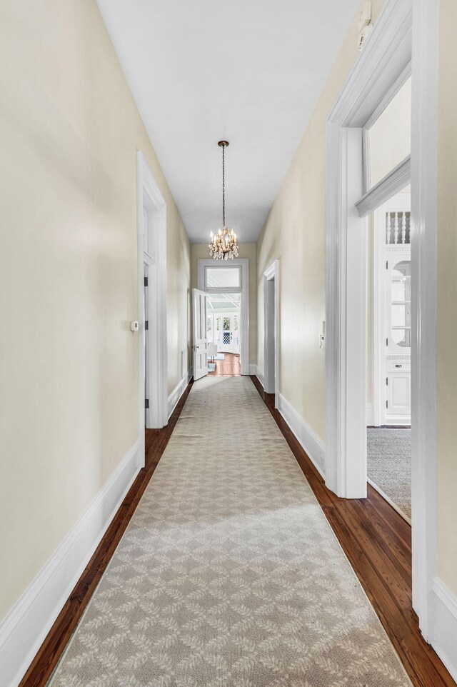 hall featuring a notable chandelier and dark hardwood / wood-style flooring