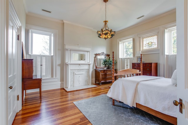 bedroom featuring an inviting chandelier, crown molding, hardwood / wood-style flooring, and multiple windows