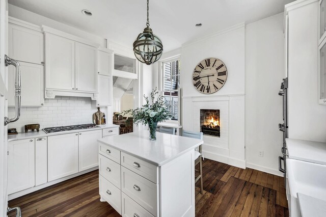 kitchen featuring a center island, stainless steel gas cooktop, dark hardwood / wood-style floors, and white cabinetry