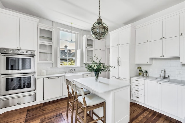 kitchen with double oven, dark wood-type flooring, sink, and white cabinets