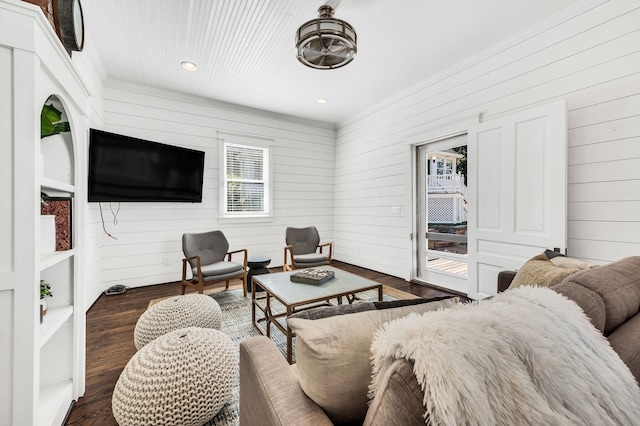 living room featuring plenty of natural light, dark wood-type flooring, and wood walls