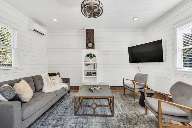 living room featuring a healthy amount of sunlight, a wall unit AC, wooden walls, and dark hardwood / wood-style flooring