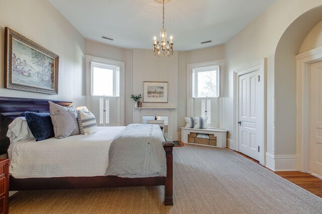 bedroom with hardwood / wood-style floors, an inviting chandelier, and multiple windows