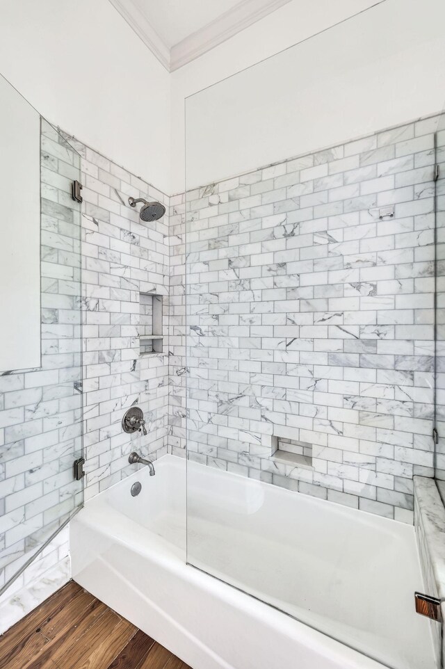 bathroom with wood-type flooring, tiled shower / bath combo, and ornamental molding