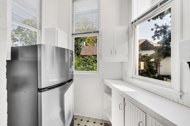 interior space featuring stainless steel fridge, a wealth of natural light, and white cabinetry