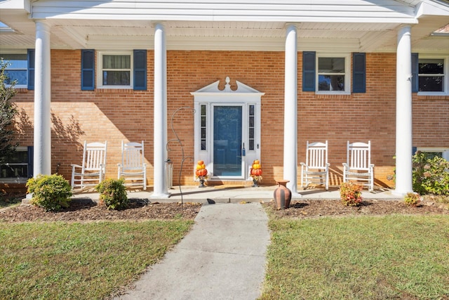 entrance to property with a yard and covered porch