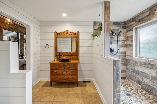 bathroom with vanity, a shower, wooden walls, and a textured ceiling