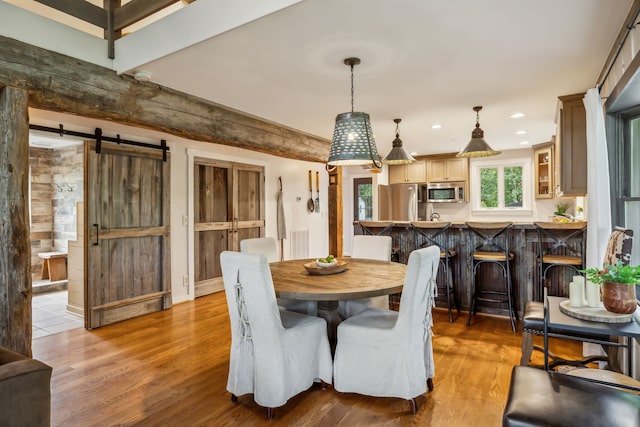 dining area with hardwood / wood-style floors and a barn door