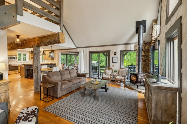 living room featuring wooden walls, hardwood / wood-style floors, a wood stove, and high vaulted ceiling