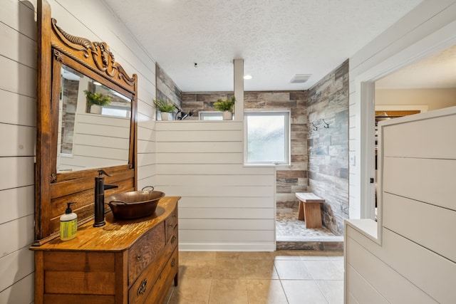 bathroom featuring tile patterned flooring, wood walls, a textured ceiling, and vanity