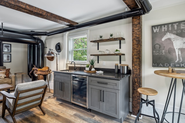 bar with dishwasher, light hardwood / wood-style floors, beamed ceiling, sink, and gray cabinetry