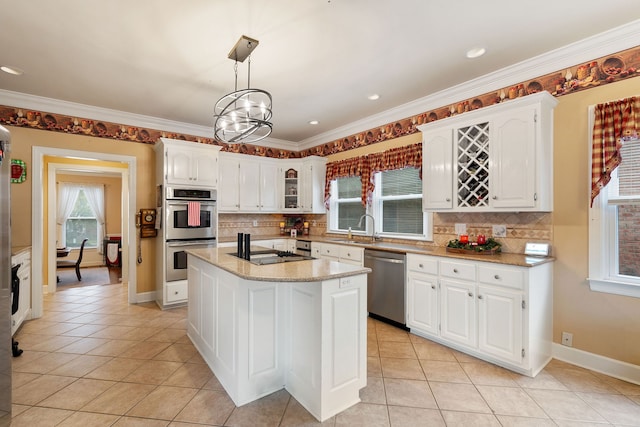 kitchen with white cabinets, appliances with stainless steel finishes, decorative light fixtures, and a center island