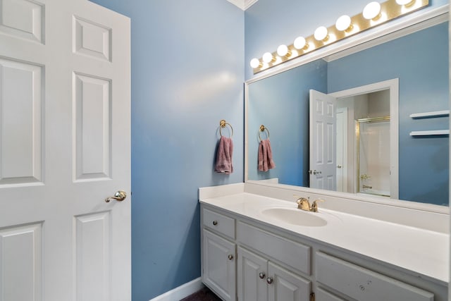 bathroom with a shower with shower door, vanity, and ornamental molding