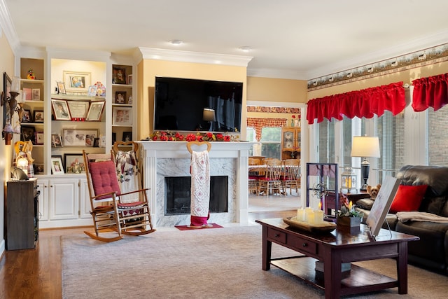 living room featuring a premium fireplace, built in shelves, light hardwood / wood-style floors, and crown molding