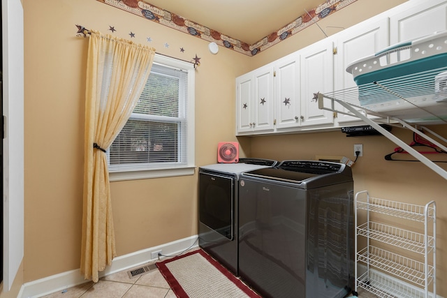 washroom featuring cabinets, washing machine and dryer, and light tile patterned floors