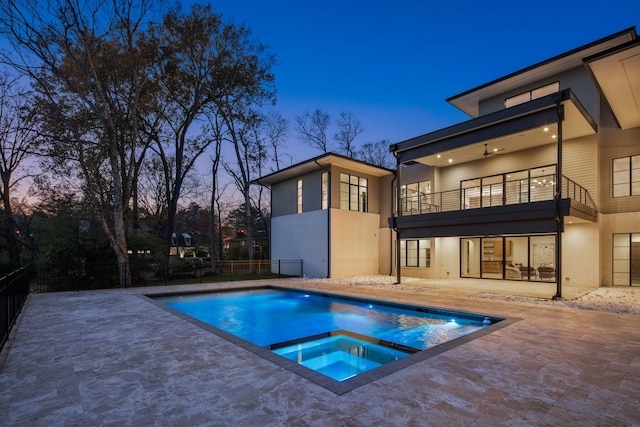 pool at dusk with ceiling fan, a patio area, and an in ground hot tub