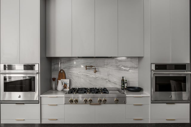 kitchen featuring white cabinets, light stone countertops, stainless steel appliances, and tasteful backsplash