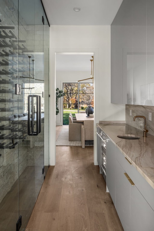 hallway with sink, beverage cooler, and hardwood / wood-style floors