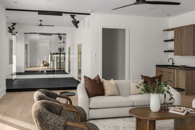 living room with ceiling fan, sink, and light hardwood / wood-style floors