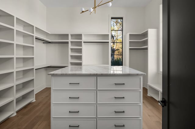 walk in closet featuring dark hardwood / wood-style flooring and a notable chandelier