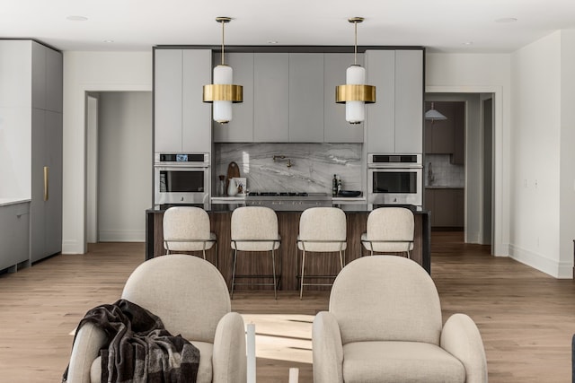 kitchen featuring gray cabinets, light hardwood / wood-style floors, and stainless steel oven