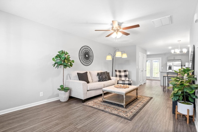 living room with ceiling fan with notable chandelier and dark hardwood / wood-style floors