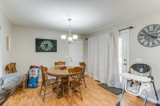 dining space with light hardwood / wood-style flooring and an inviting chandelier