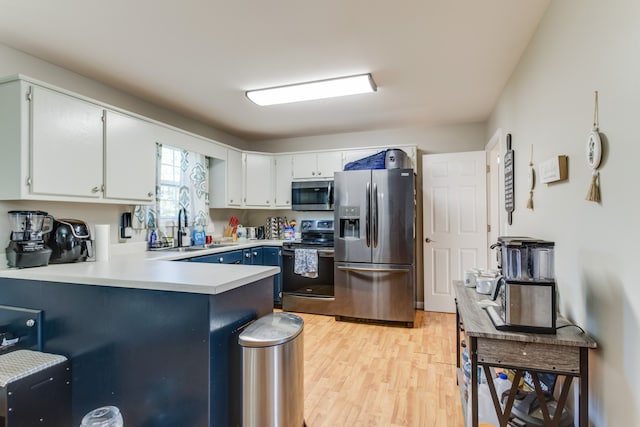 kitchen with light wood-type flooring, sink, white cabinetry, kitchen peninsula, and appliances with stainless steel finishes