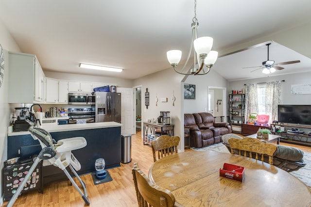 dining space with ceiling fan with notable chandelier, lofted ceiling, and light hardwood / wood-style flooring