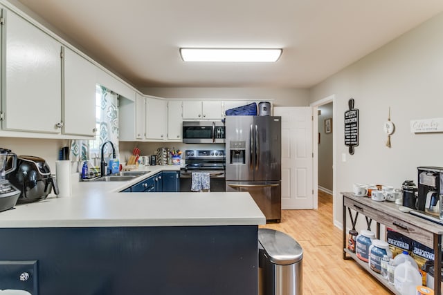 kitchen featuring light hardwood / wood-style floors, sink, white cabinetry, kitchen peninsula, and stainless steel appliances