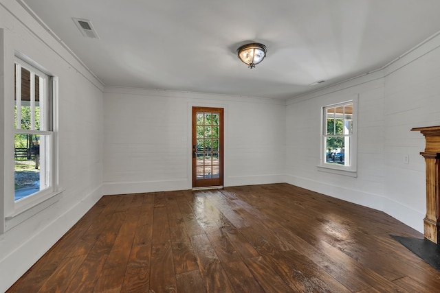 unfurnished living room featuring dark hardwood / wood-style flooring and crown molding