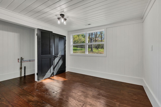 interior space featuring dark hardwood / wood-style floors and wooden walls