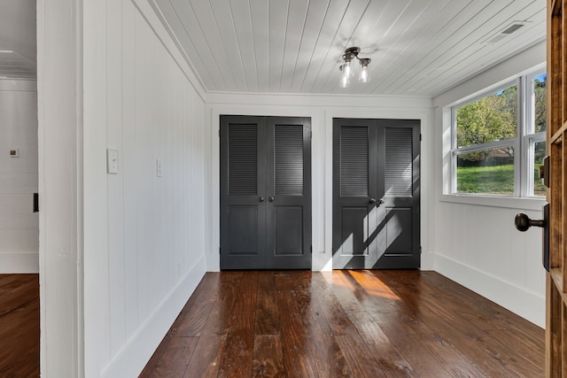 entryway with dark wood-type flooring, wood ceiling, and wooden walls