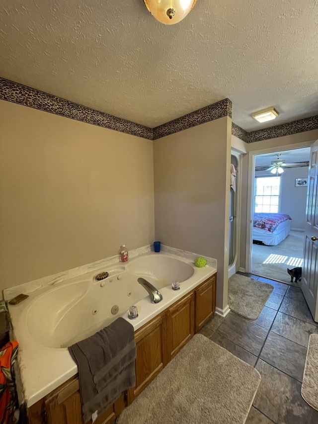 ensuite bathroom with connected bathroom, a tub with jets, a textured ceiling, and a stall shower