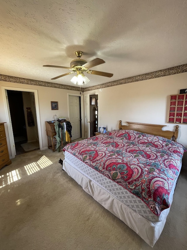 carpeted bedroom with a closet, a ceiling fan, a textured ceiling, and ensuite bathroom
