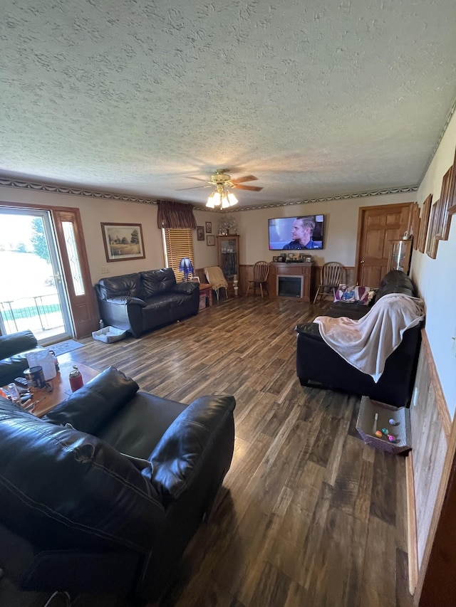 living room with a ceiling fan, dark wood-style flooring, and a textured ceiling