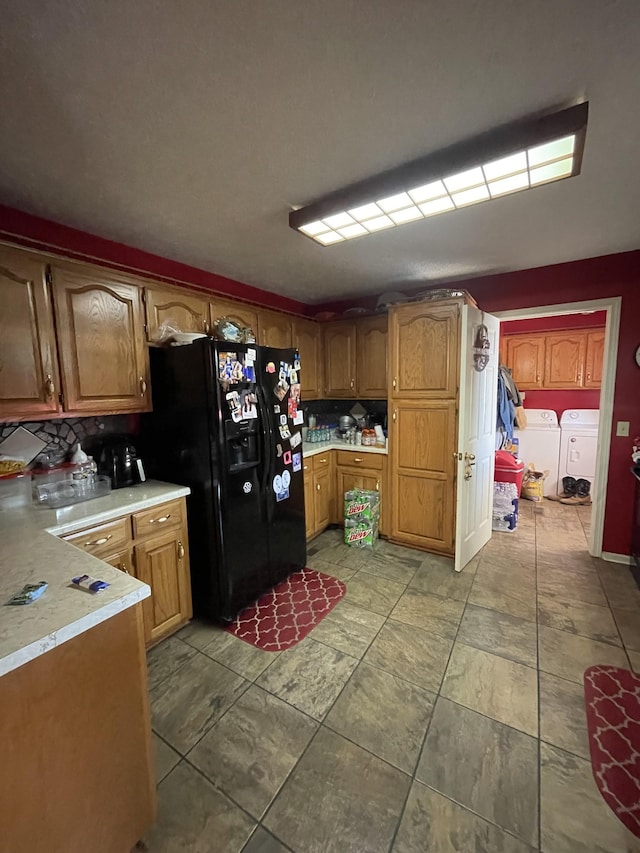 kitchen with washing machine and clothes dryer, black fridge with ice dispenser, light countertops, and brown cabinets