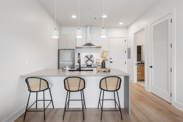 kitchen featuring stainless steel fridge, island range hood, white cabinets, and pendant lighting