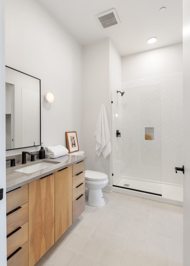 bathroom featuring tile patterned floors, vanity, toilet, and a tile shower