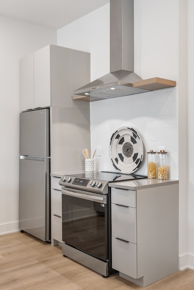 kitchen with white cabinetry, light wood-type flooring, wall chimney range hood, and appliances with stainless steel finishes