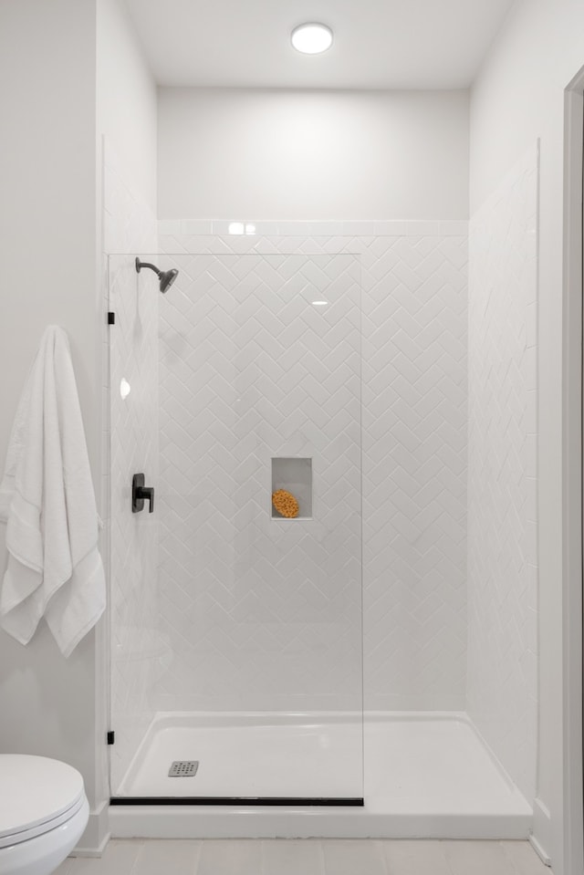 bathroom with a tile shower and toilet