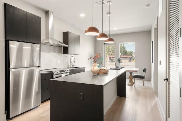 kitchen with visible vents, wall chimney exhaust hood, appliances with stainless steel finishes, light wood-style floors, and a sink