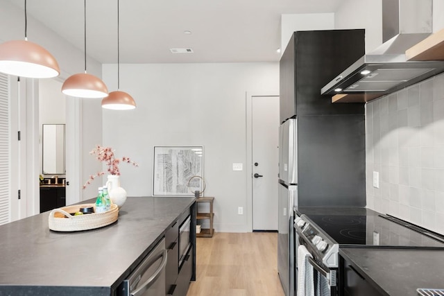 kitchen featuring visible vents, appliances with stainless steel finishes, wall chimney exhaust hood, light wood finished floors, and dark countertops