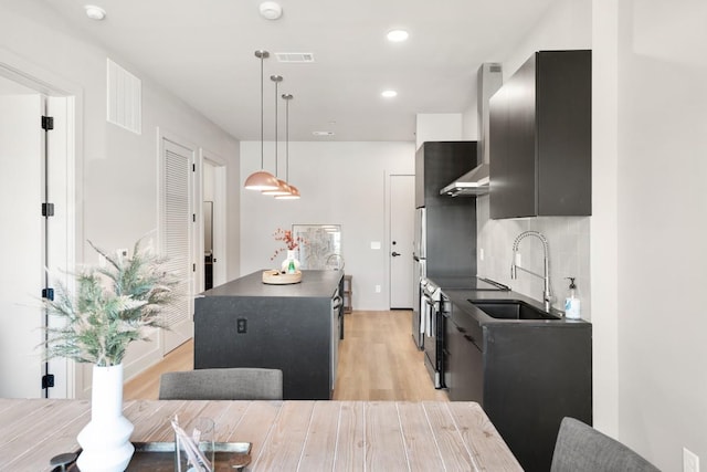 kitchen with a kitchen island, a sink, visible vents, dark cabinetry, and dark countertops