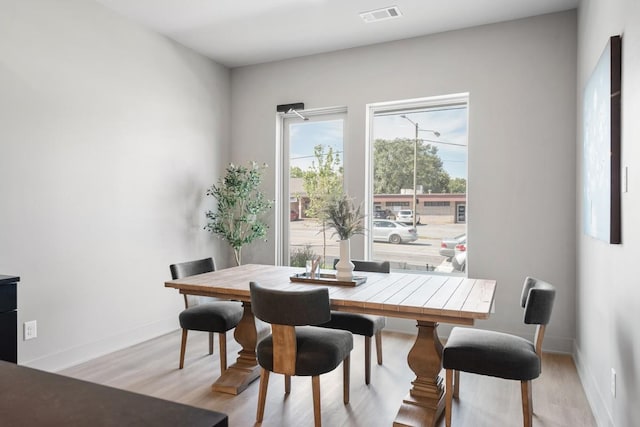 dining area featuring visible vents, light wood-style flooring, and baseboards