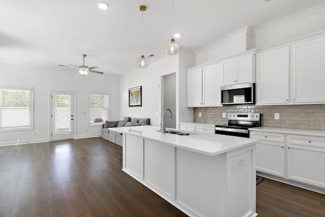 kitchen featuring a center island with sink, sink, hanging light fixtures, white cabinets, and appliances with stainless steel finishes