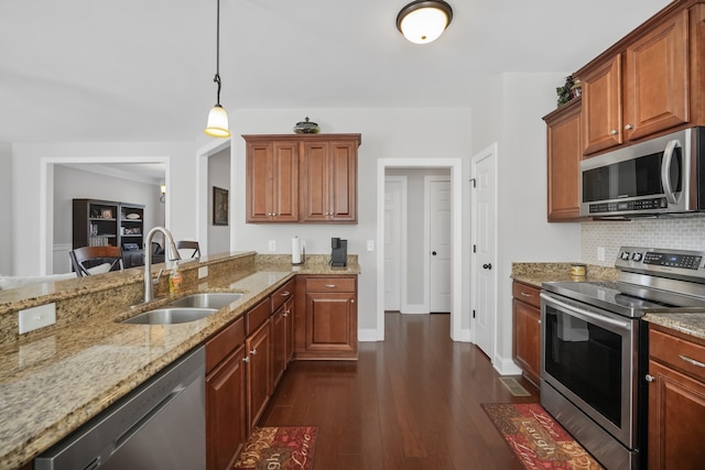 kitchen with dark hardwood / wood-style floors, sink, light stone counters, stainless steel appliances, and hanging light fixtures