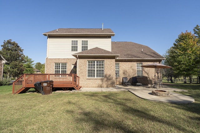 rear view of property featuring a patio, a fire pit, a lawn, and a wooden deck