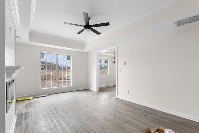 unfurnished living room featuring hardwood / wood-style flooring, ceiling fan, ornamental molding, and a tray ceiling