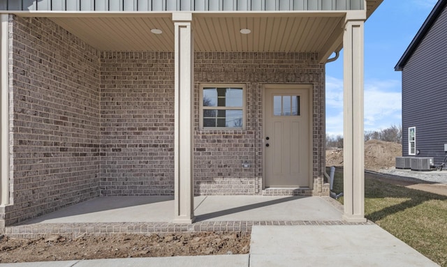 view of exterior entry featuring brick siding and board and batten siding